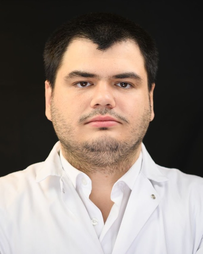 Portrait of Mert Gezek in a white lab coat.